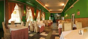 a restaurant with white tables and green walls at Volter Hotel in Lviv