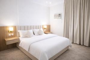 a bedroom with a large bed with white sheets and pillows at Smo Hail سمو حائل in Hail