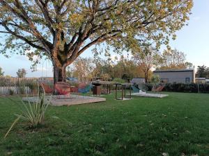 a park with chairs and a table under a tree at Tiny house Oléroncoast La-Brée-Les-Bains in La Brée-les-Bains