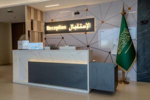 a reception desk with a sign and a flag at Aurion AsSalaam Hotel Apartment in Medina