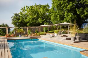 a swimming pool with tables and umbrellas and chairs at Domaine Aari Ona in Aramits
