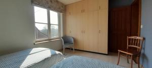 a bedroom with a bed and a window and a chair at Vakantiewoning Zoetebeek in Oudenaarde
