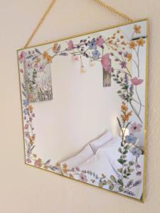 a mirror hanging on a wall with flowers at The Sunny Side Apartment in Florina