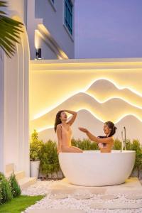 two women sitting in a bath tub in a building at Brown Empire Pool Villa Pattaya in Nong Prue