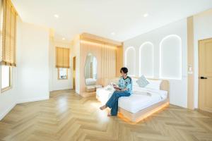 a woman sitting on a couch in a living room at Brown Empire Pool Villa Pattaya in Nong Prue