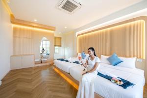 a woman sitting on two beds in a hotel room at Brown Empire Pool Villa Pattaya in Nong Prue