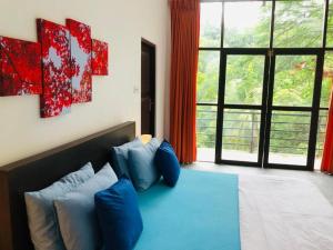 a bedroom with a bed with blue pillows and a window at Red lettter hotel in Nikawatawana