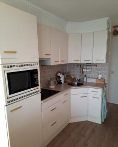 a kitchen with white cabinets and a microwave at Het Goudvinkennestje in Matsloot