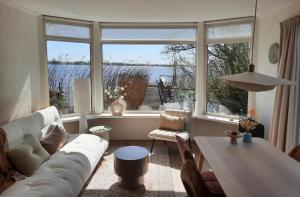 a living room with a white couch and a large window at Het Goudvinkennestje in Matsloot