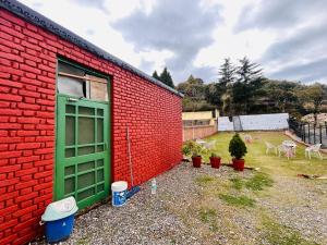 a red brick building with a green door next to a yard at Banj View Resort in Mussoorie