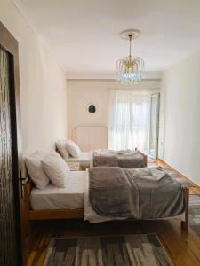 two beds in a room with a chandelier at The Sunny Side Apartment in Florina +12 photos