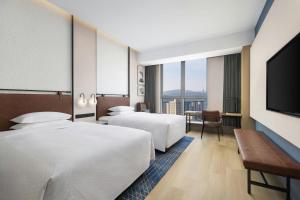 a hotel room with two beds and a flat screen tv at Four Points by Sheraton Tianshui in Tianshui +12 photos