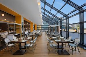 a restaurant with tables and chairs and a large glass ceiling at Le Meridien, Surat in Surat