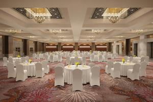 a banquet hall with white tables and chairs and chandeliers at Le Meridien, Surat in Surat +29 photos