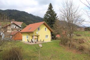 a yellow house with a red roof in a field at Narrenhaus in Fohnsdorf