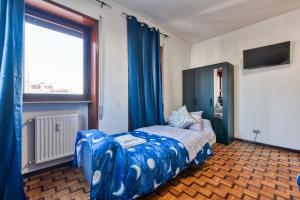 a bedroom with a bed with blue curtains and a window at Easy Downtown Inn in Marghera