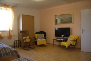 a living room with yellow chairs and a television at Narrenhaus in Fohnsdorf