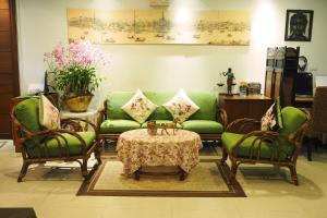 a living room with a green couch and chairs and a table at Baan Sukhumvit Soi 18 in Bangkok