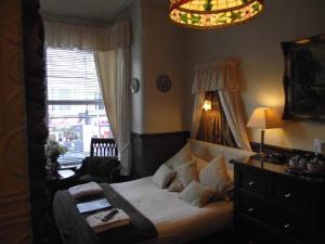 a bedroom with a bed and a chair and a window at The Molly House in Blackpool