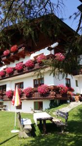 a building with pink flowers and a table and an umbrella at Alpenhaus Birkhahn in Ramsau am Dachstein