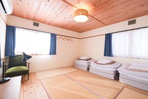 a room with two beds and a chair at アブラサカスペース in Nara