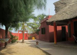 a fire hydrant in front of a red building with palm trees at Oasis Palmarin in Palmarin