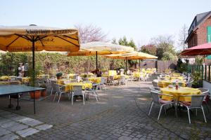 a group of tables and chairs with yellow tables and umbrellas at Kastanienhof in Mönchengladbach