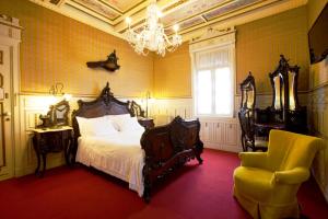 a bedroom with a bed and a chair and a chandelier at Castelo Santa Catarina in Porto