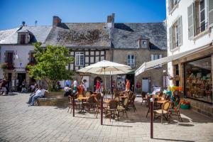 um pátio exterior com mesas, cadeiras e um guarda-sol em Au Fin Gourmet em Le Croisic