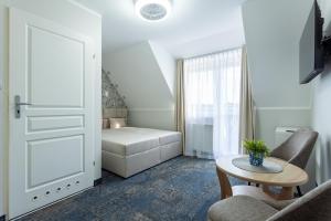 a room with a bed and a table and a door at POKOJE APARTAMENTY ANASTAZJA in Grzybowo