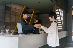 a man and a woman shaking hands at a counter at APARTMENTS by Bed and Craft in Inami