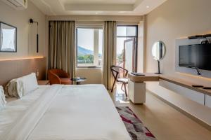a hotel room with a bed and a desk and a tv at Hotel Yog Vashishth in Rishīkesh +52 photos