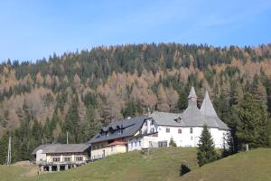 une grande maison blanche sur une colline avec une forêt dans l'établissement Hüttentraum Flattnitz, à Flattnitz