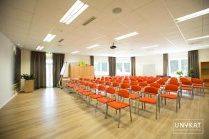 an empty room with orange chairs and a podium at Hotel Sole Felsen Welt in Gmünd +59 photos