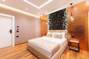 a bedroom with a large white bed and a wall at Bliss Boutique Hotel in Durrës