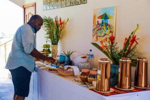 a man standing in front of a table with food at GINFORM at Hotel Petit Brussel in Lomé