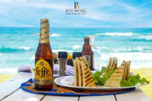 a table with a plate of food and two bottles of beer at GINFORM at Hotel Petit Brussel in Lomé
