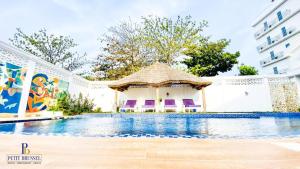 a swimming pool with a gazebo next to a building at GINFORM at Hotel Petit Brussel in Lomé
