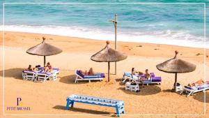 a group of people sitting on a beach with umbrellas at GINFORM at Hotel Petit Brussel in Lomé +24 photos