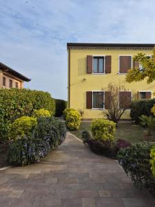 ein gelbes Haus mit einem Gehweg in einem Garten in der Unterkunft AnimAntica in Lido di Pomposa