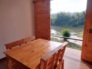 a wooden table and bench with a view of a river at Wangpocamping วังโพแค้มป์ปิ้ง in Ban Wang Pho