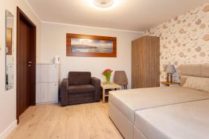 a bedroom with a bed and a chair at POKOJE APARTAMENTY ANASTAZJA in Grzybowo