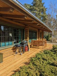 a porch of a log cabin with a grill and a bench at Blockhaus Fleesensee in Silz