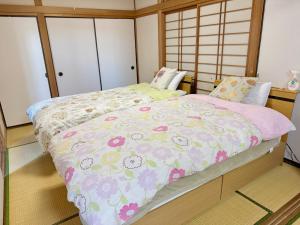 a bedroom with a bed with a floral comforter at 別府ホーム in Beppu