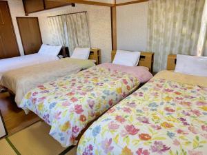 a room with three beds with floral sheets at 別府ホーム in Beppu