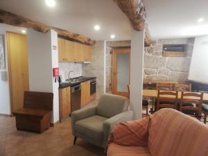 a living room with a couch and a table and a kitchen at Sambuc'asa - Serra da Estrela in Sabugueiro
