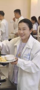 a woman in a kitchen holding a plate of food at J P PALACE in Kushinagar