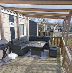 a patio with a couch and a table on a deck at Chalet Lauwersoog mét airco! in Lauwersoog