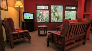 - un salon avec deux chaises et une télévision dans l'établissement Lar Aike, à El Calafate
