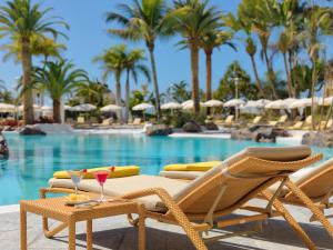 a pool with lounge chairs and a table with drinks at Adrián Hoteles Jardines de Nivaria in Adeje